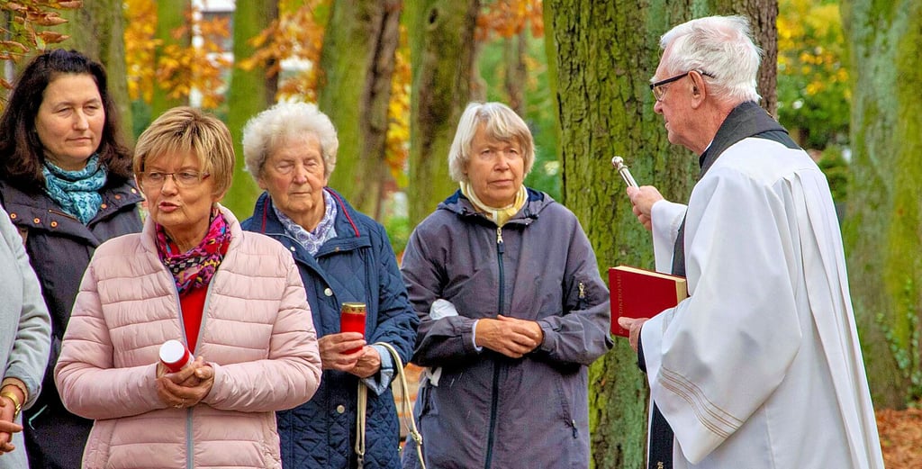 Pfarrer Peter Zülicke segnet die Grabkerzen auf dem Wolmirstedter Friedhof. Der Pfarrer hatte am Wochenende mehrere Friedhöfe in der Region besucht.