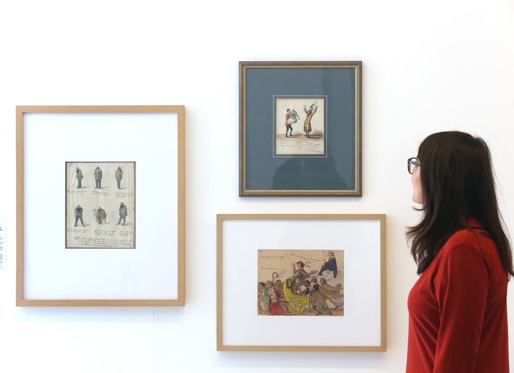 Eine Zeichenserie von Graf von Pocci (1850) schaut sich in der Ausstellung "Unveröffentlicht - Die Comicszene packt aus" eine Fachbesucherin an.
