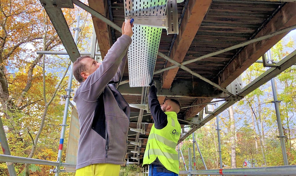 Aiko Fincke (l.) und Francis Machemehl montieren die neue Kabeltrasse unter der Vossbrücke.
