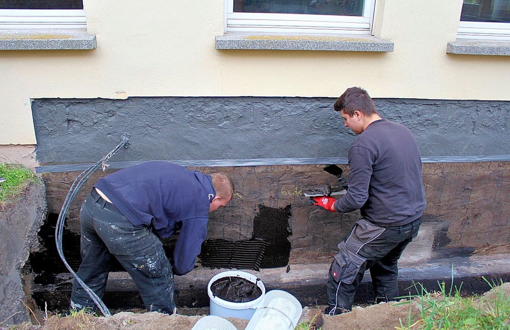 Die Männer von der Firma Bautenschutz Otte bringen die wasserundurchlässige Bitumenschicht auf.