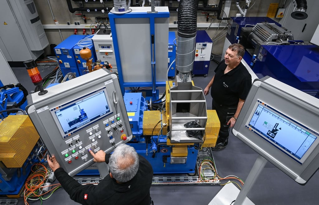 Mitarbeiter bestücken im neuen Technikum eine Compoundieranlage für Elastomerverarbeitung.