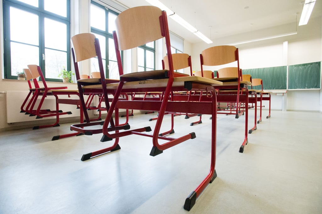 Stühle stehen auf Tischen in einem leeren Klassenzimmer einer Schule, ein solches Bild kommt beispielsweise bei hohem Unterrichtsausfallzustande.