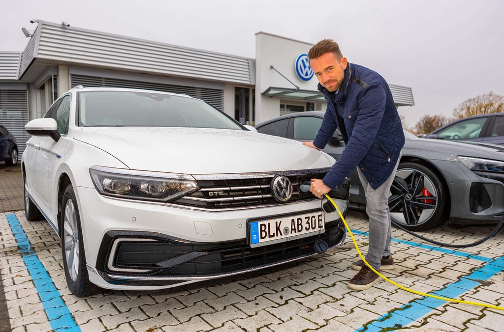 Geschäftsführer Gilbert Baumann vom Autohaus Baumann lädt einen Hybridwagen mit Strom auf.