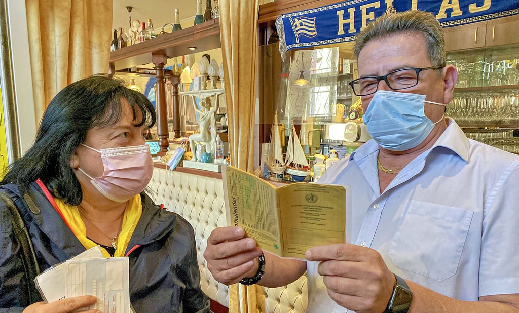 Kathrin Hoffmann zeigt Ilias Dimitriou ihren Impfpass