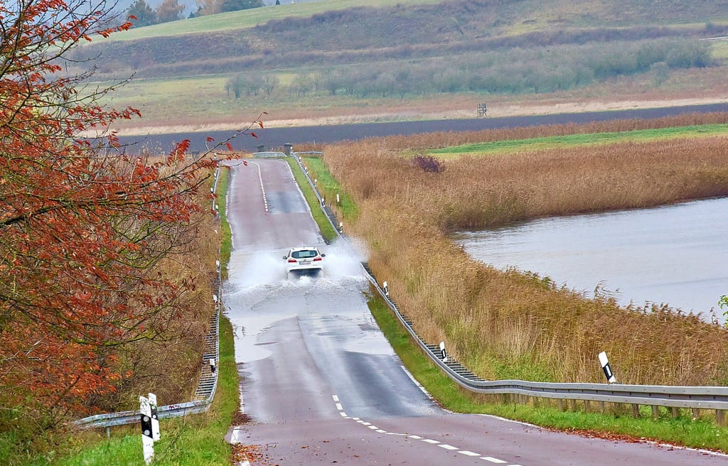 Auf dieser Aufnahme aus der Ferne sieht die Überschwemmung gerade noch wie eine große Pfütze aus. Gesperrt ist die Landesstraße dennoch.