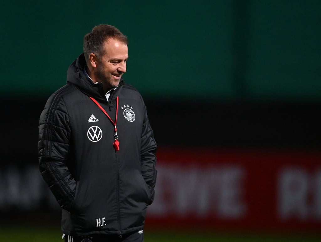 Der Mann mit der roten Trillerpfeife: Bundestrainer Hansi Flick steht lächelnd auf dem Platz.
