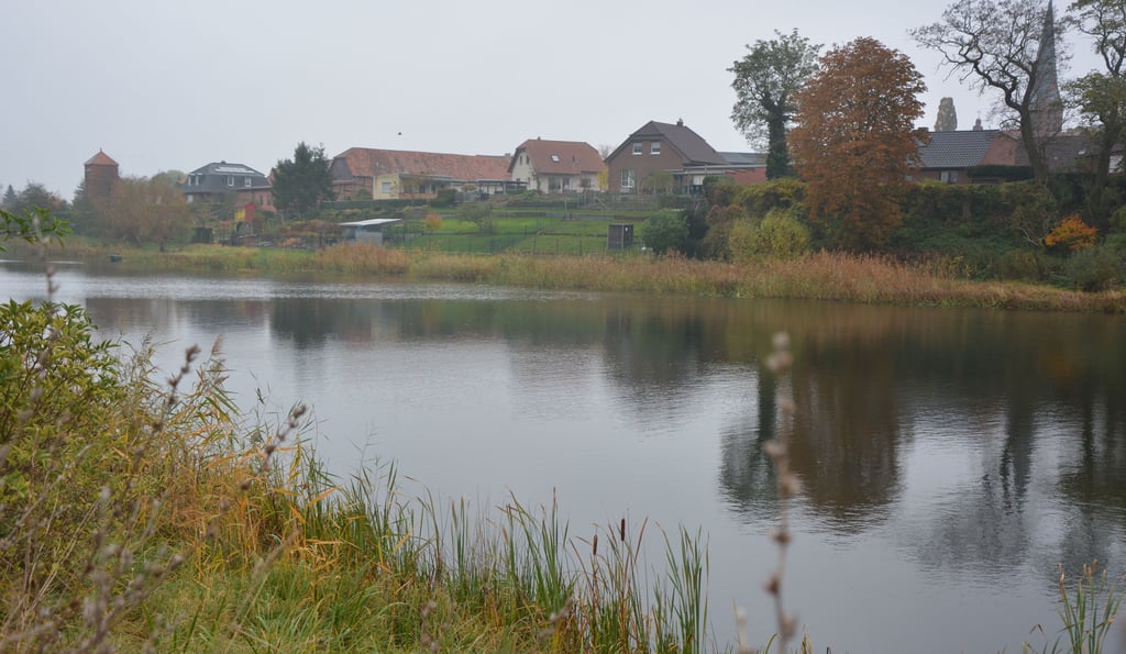 Der herbstlich eingebettete Parchauer See Richtung Osten mit Kirche (rechts) und Trafostation links. Das Gewässer sollte ursprünglich mit den Teil-Seen entschlammt werden. Jetzt liegt das Projekt aus Kostengründen vorerst auf Eis.