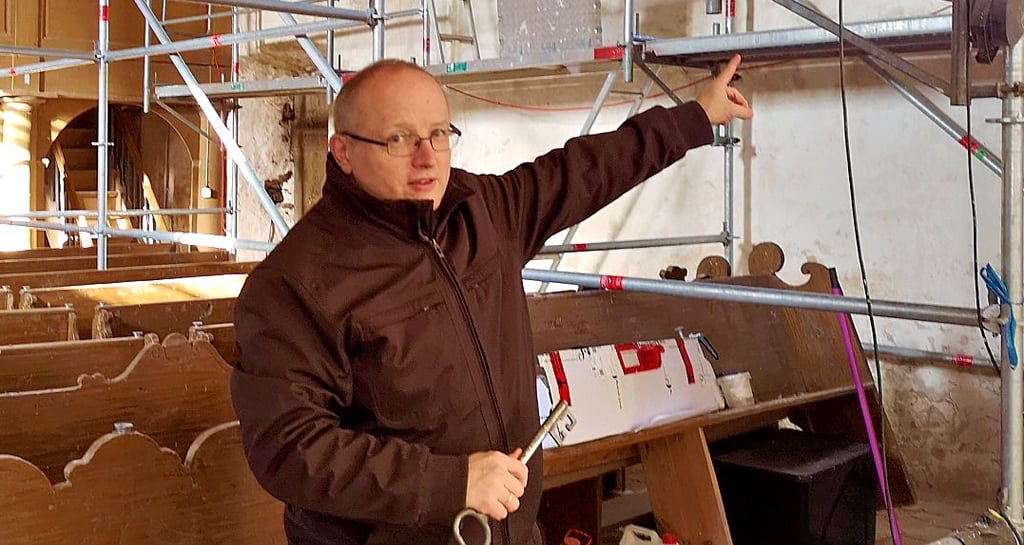 Pastor Andreas Henke deutet auf mittelalterliche Wandmalereien im Kirchenschiff der Dambecker Kirche, die zu den ältesten in der Altmark gehören sollen.