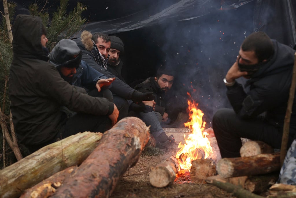 Flüchtlinge bei Grodno in Weißrussland wäremn sich am Feuer.