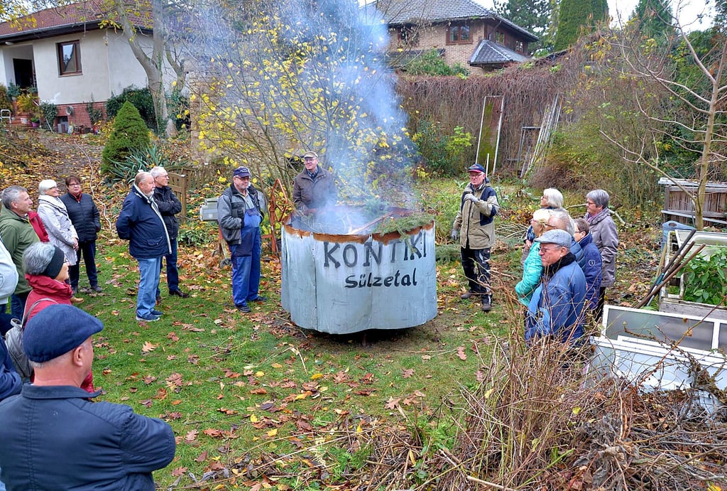 Klaus Jacobs erläutert über 50 Besuchern bei einem Schaubrennen auf seinem Hof die Herstellung von Pflanzenkohle in einem Kontiki-Ofen.