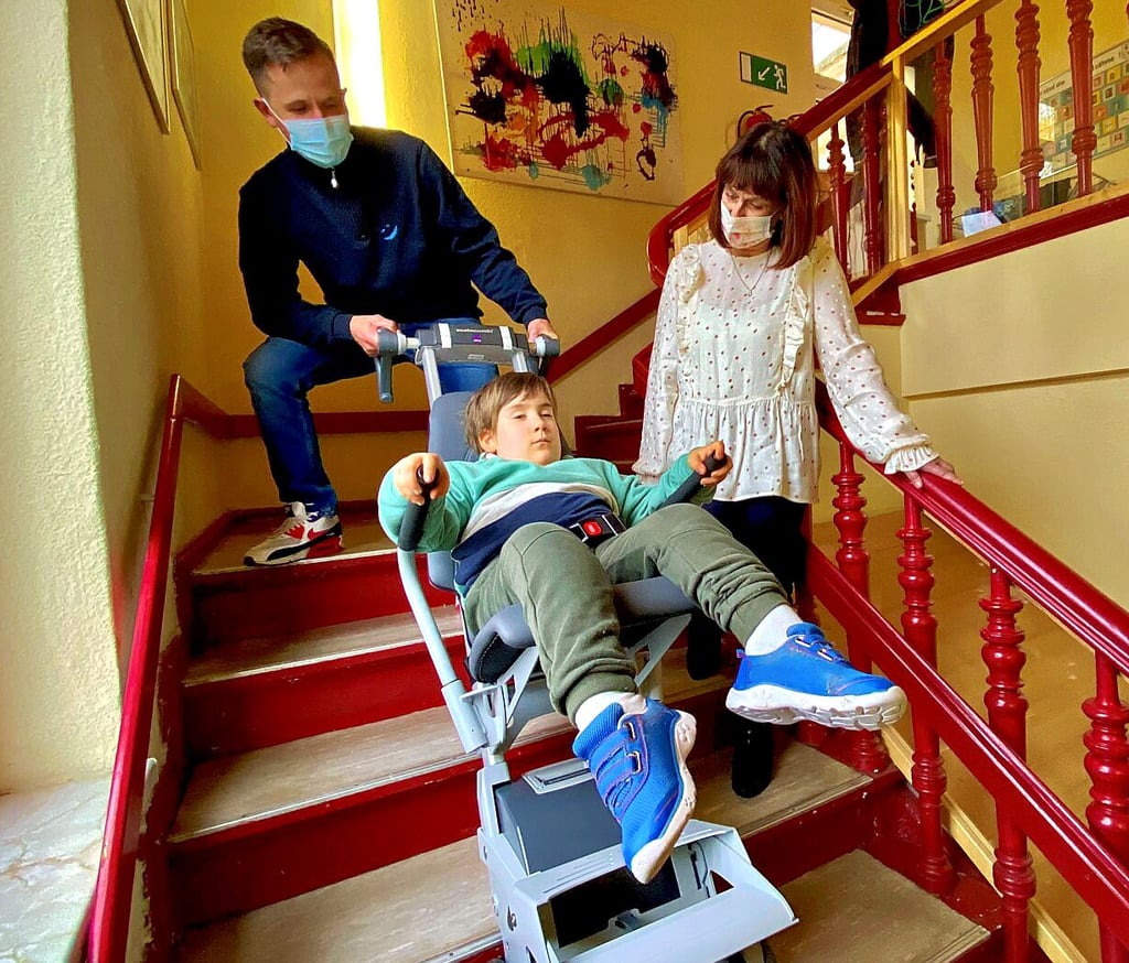 Reha-Techniker David Leuschner (links) und Kita-Leiterin Sabine Herrmann begleiten Marvin die Treppe nach oben.
