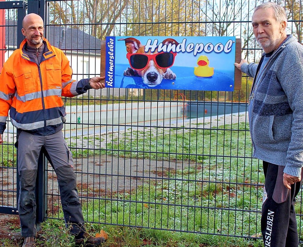 Nico Sosath (l.) und Ortsbürgermeister Hans-Eike Weitz zeigen das pfiffige Schild für das künftige Hundeschwimmen.