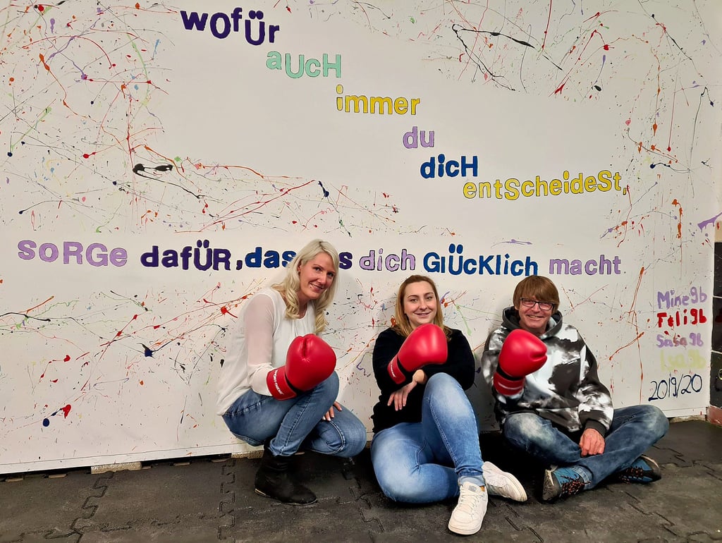 Claudia Fröhlich, Anika Hendrich und Sylvio Huth sitzen in dem Anti-Aggressionsraum vor einer von Schülern gestalteten Wand.