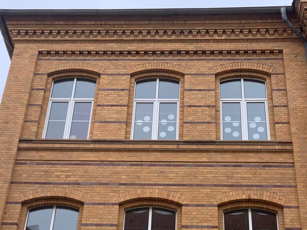 Die Fenster der Schule weisen kreisrunde Beschädigungen an der äußeren Scheibe der Doppelverglasung auf.