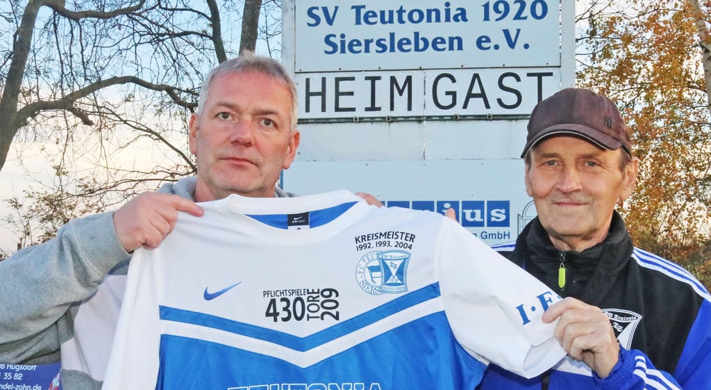Jens Heise und Herbert Deinzer mit dem Trikot, auf dem die aussergewöhnlichen Daten der Fußballer-Laufbahn des 50-Jährigen vermerkt sind.