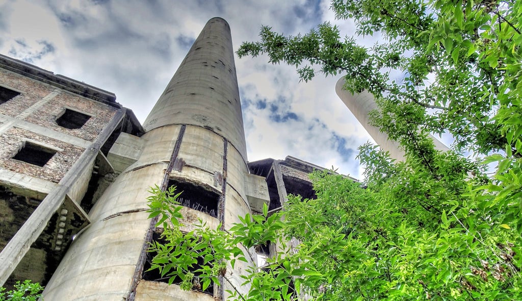 Zwischen einer Kleingartenanlage und dem Oder-Neiße-Radwanderweg ragt die Ruine des Kraftwerks Vogelsang bei Eisenhüttenstadt 100 Meter hoch auf.