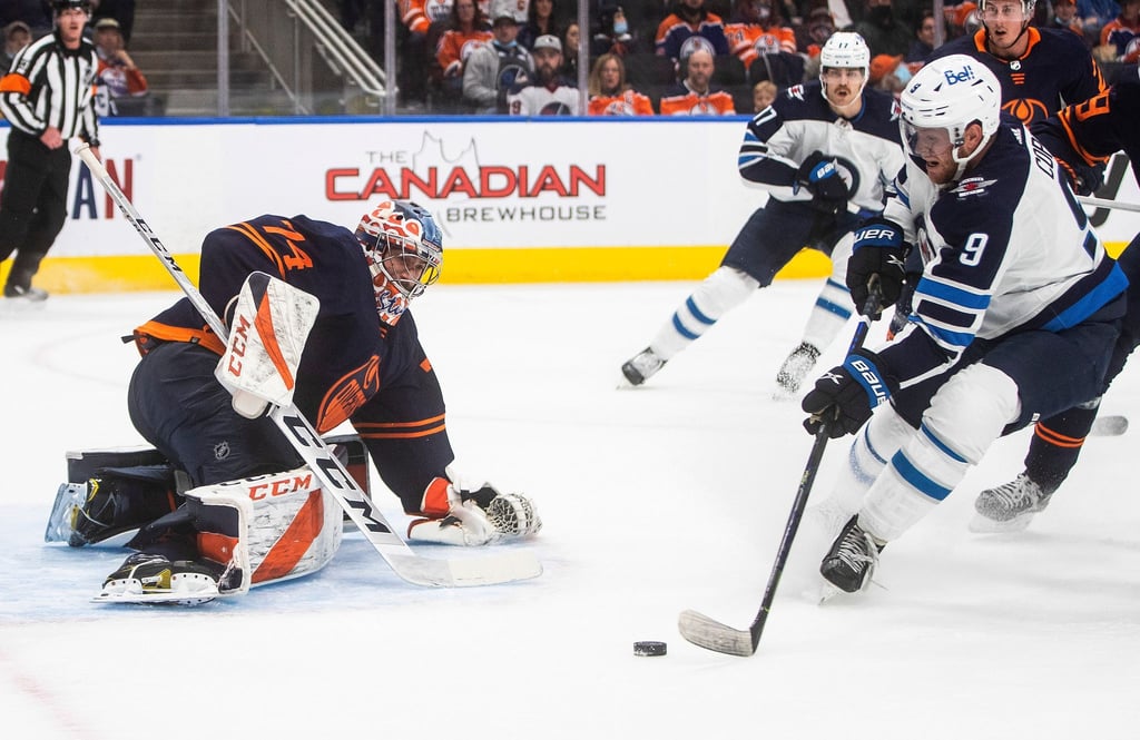 Andrew Copp (r) von den Winnipeg Jets gegen Edmonton Oilers Torwart Stuart Skinner (l).