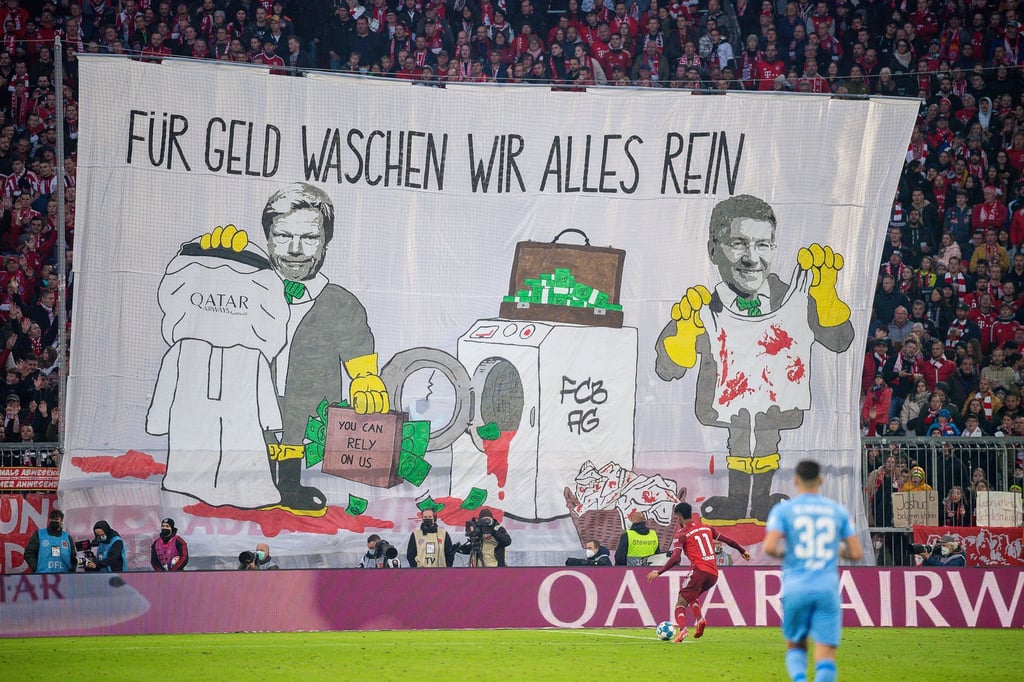 Mit einem Transparent „Für Geld waschen wir alles rein“ protestieren Münchner gegen die Geschäftsbeziehungen des Rekordmeisters.