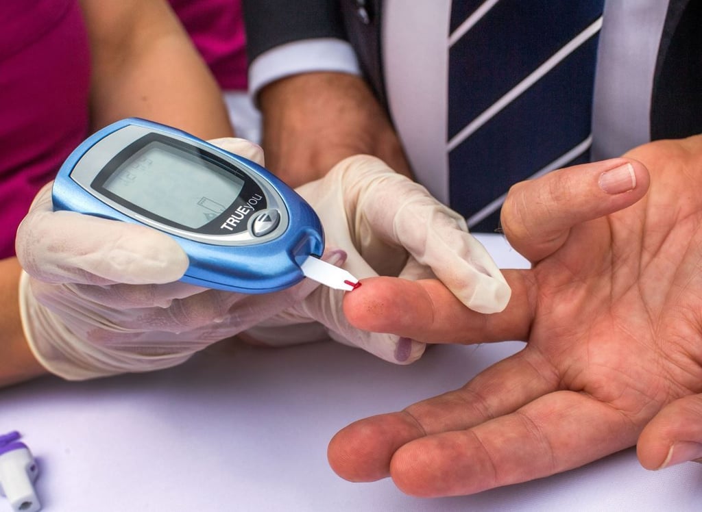 Ein Mann lässt sich von einer Diabetesberaterin eine Blutprobe für einen Blutzuckertest nehmen.