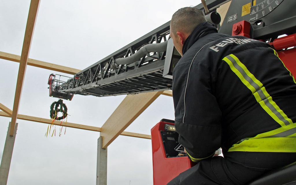 Aus der künftigen Fahrzeughalle heraus: Ortswehrleiter Andreas Beinroth manövriert den Richtkranz über die Dachkonstruktion.