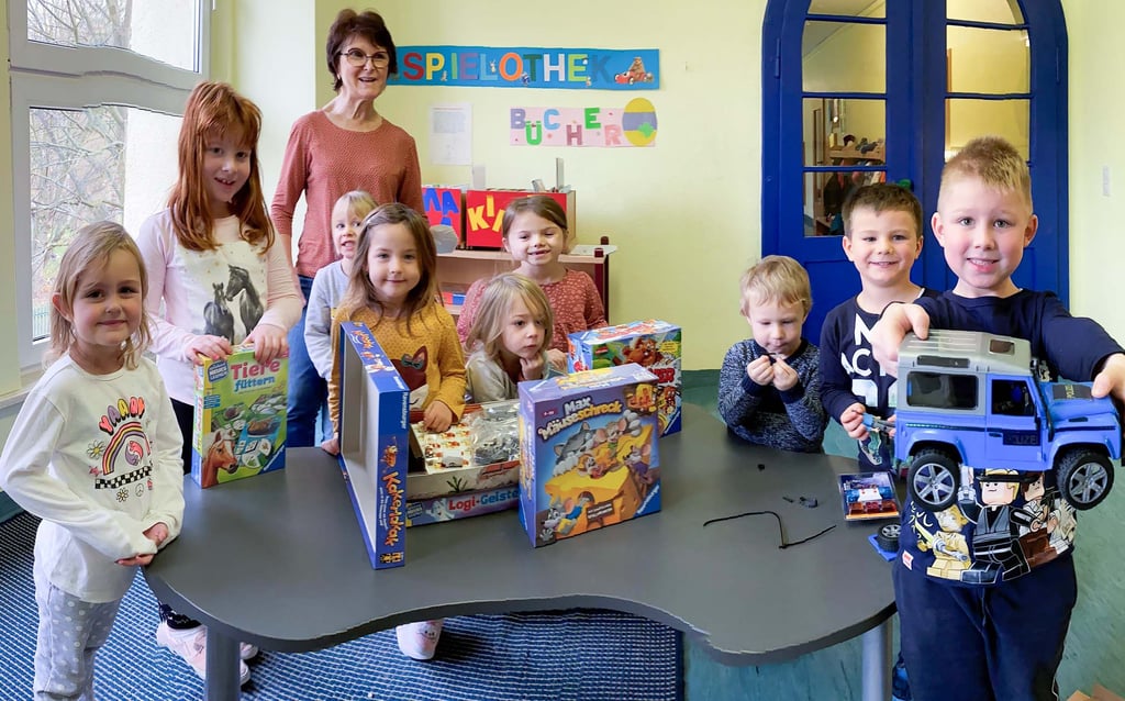 Voller Freude haben die Kinder der Kita „Pusteblume“ sowie Kita-Leiterin Gisela Schulz (hinten) das Spielepaket geöffnet. Dem sechsjährigen Niklas aus Klostermansfeld (re.) gefällt besonders der blaue Jeep, der neben zahlreichen Spielen auch mit zum Gewinn gehörte.