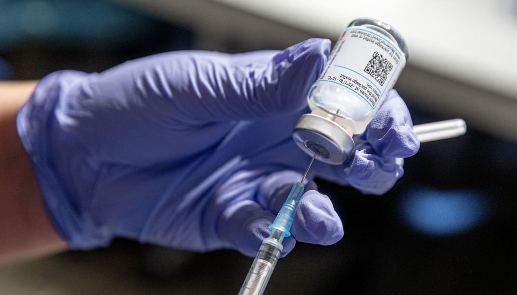 Eine Krankenschwester zieht Corona-Impfstoff aus einer Ampulle in eine Spritze auf.