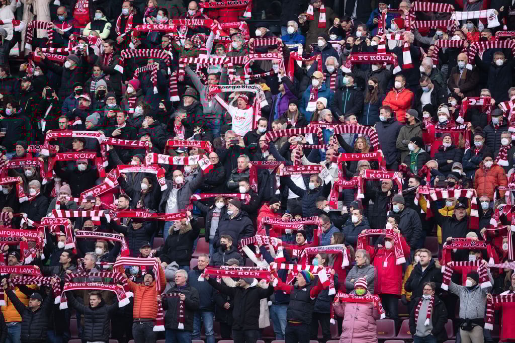 Fans des 1. FC Köln halten Fanschals in die Luft.