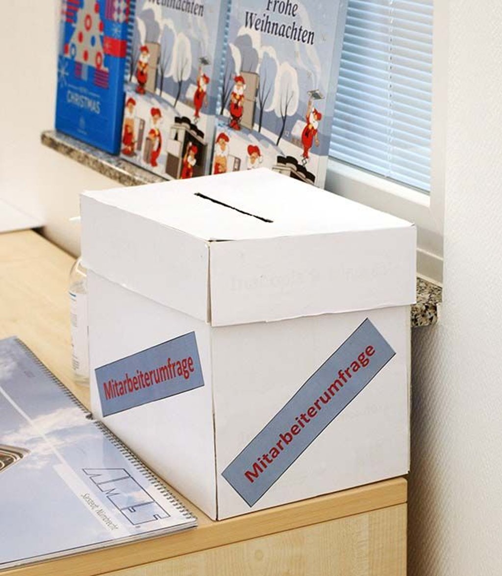 Die Sammelbox zum Einwurf der Erhebungsbögen für die aktuelle Mitarbeiterbefragung ist prominent platziert.