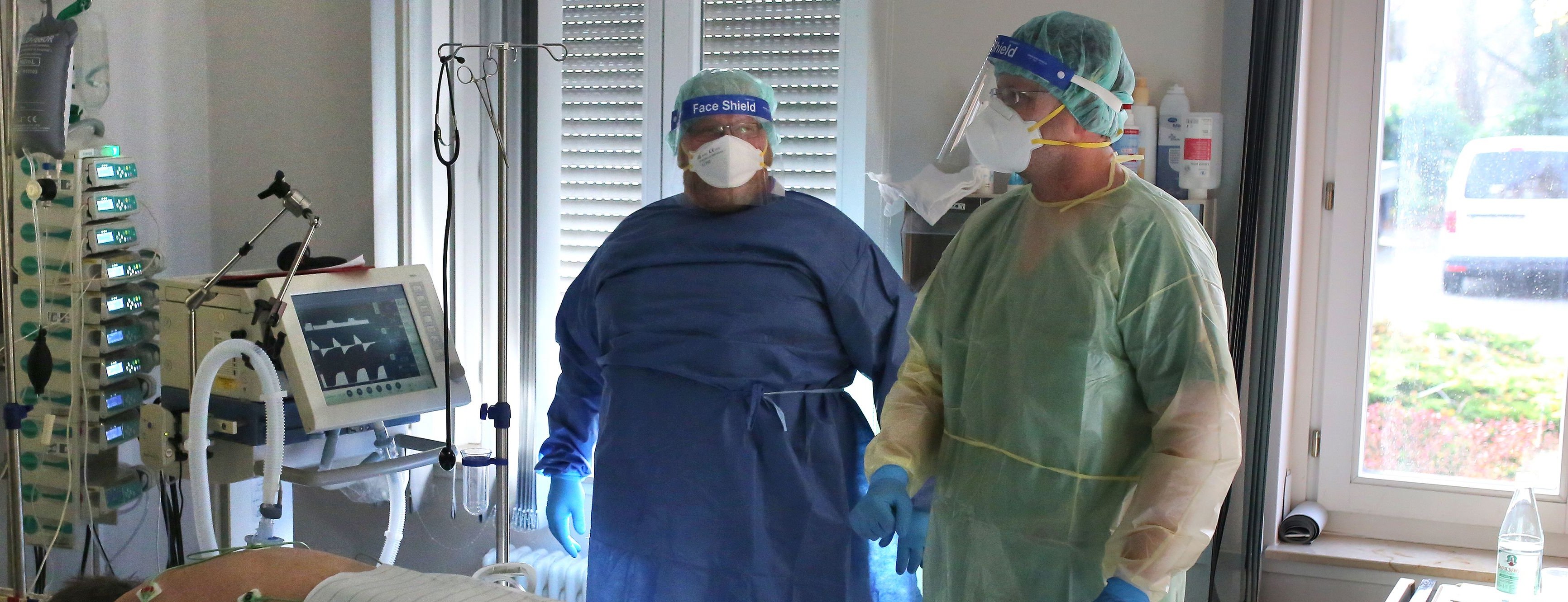 Die beiden Pfleger stehen am Bett des Patienten. Eine Corona-Infektion brachte ihn auf die Intensivstation. Er liegt auf dem Bauch, wird beatmet. Der Arbeitsalltag im Klinikum hat sich seit Pandemiebeginn verändert. Die Arbeit unter den Schutzanzügen ist anstrengend.