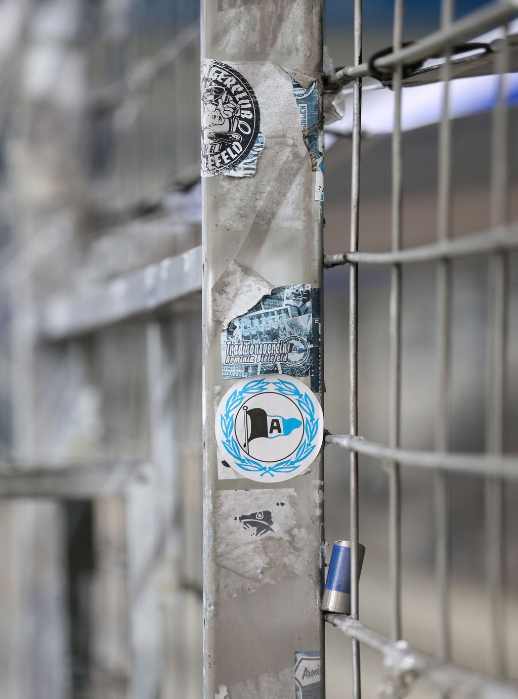 Ein Aufkleber mit dem Logo von Arminia Bielefeld klebt auf einem Zaun.