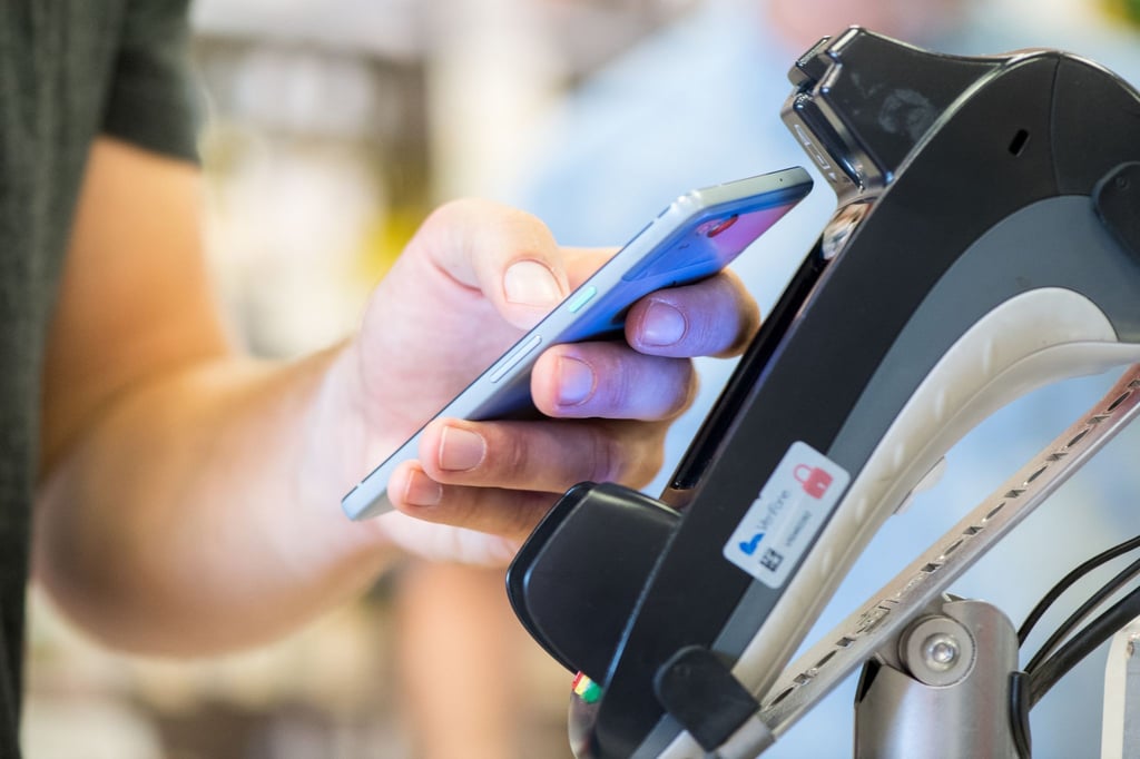 Ein Smartphone wird an ein Kassenterminal gehalten. Mit der entsprechenden App kann man so bezahlen.)