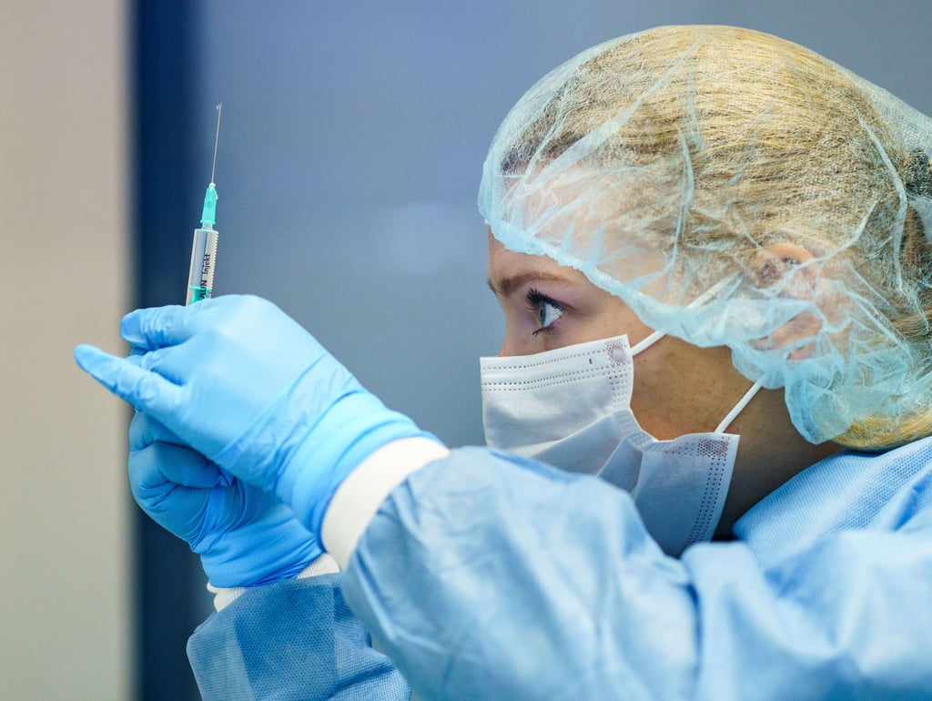 Eine Mitarbeiterin zieht zum Start der COVID-19-Auffrischungsimpfungen eine Spritze mit dem Impfoff von Biontech auf.