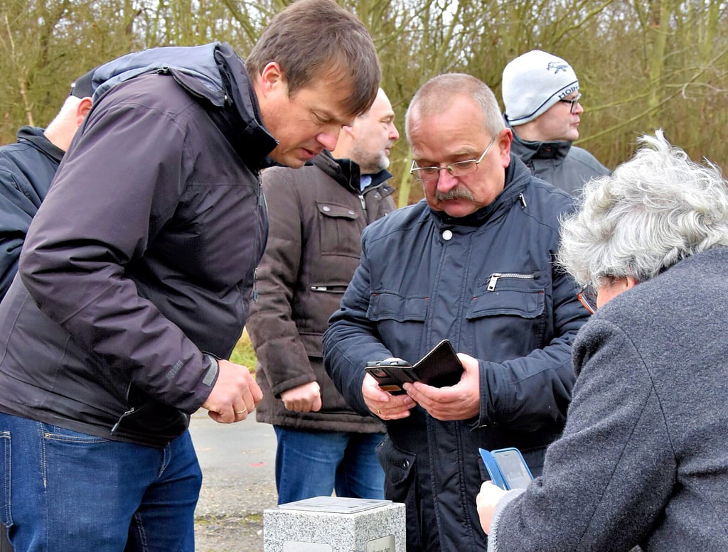 Heiko Sievers (l.), Dezernatsleiter des Landesvermessungsamtes, zeigt Wigbert Schwenke (Mitte) und Anne-Marie Keding (r.) wie anhand des geodätischen Refernzpunktes die Genauigkeit der Standortbestimmung mittels Handy funktioniert.