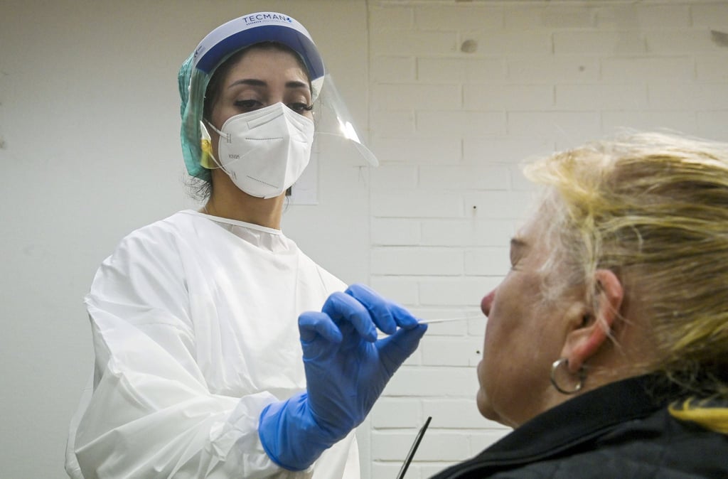 Eine medizinische Mitarbeiterin testet eine Frau auf das Coronavirus in einer Corona-Teststelle.