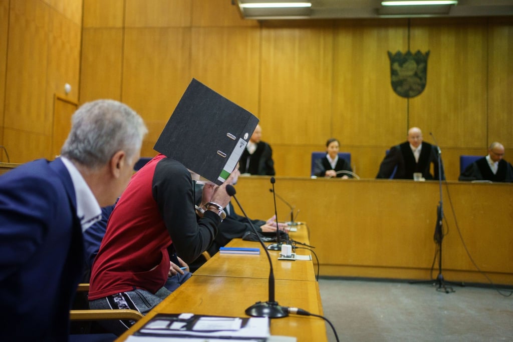 Mit einem Aktenordner vor dem Gesicht nimmt der Iraker Taha Al-J. vor der Urteilsverkündung im Frankfurter Oberlandesgericht auf der Anklagebank Platz.