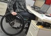 Ein Mann sitzt in einem Rollstuhl an seinem Arbeitsplatz am Schreibtisch. In Sachsen-Anhalt kommen besonders wenige Arbeitgeber ihrer Verpflichtung nach, Schwerbehinderte einzustellen.