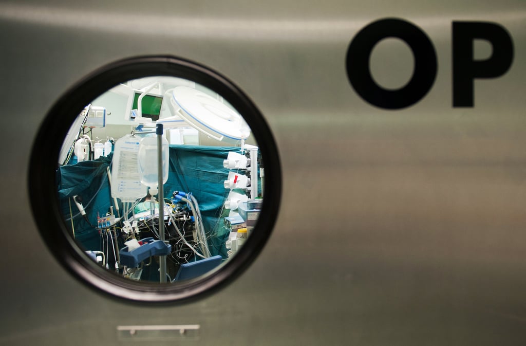 Blick durch ein Fenster in einen Operationssaal.