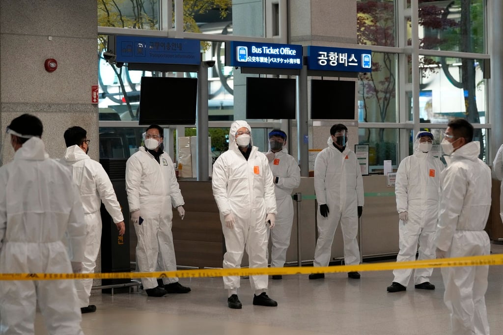 Quarantäne-Beauftragte in Schutzkleidung warten in der Ankunftshalle des internationalen Flughafens Incheon auf Reisende, um sie zu ihren Quarantäne-Unterkünften zu führen.