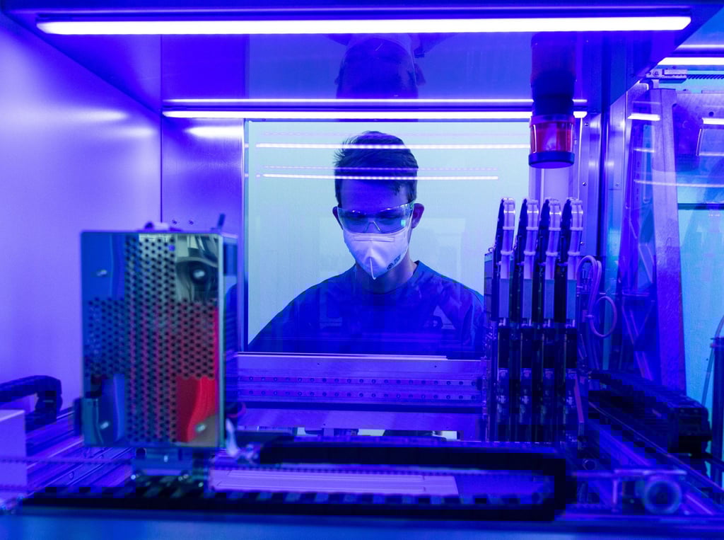 Ein Laborant untersucht in einem Labor an einem PCR-Vollautomaten Corona-Abstriche.