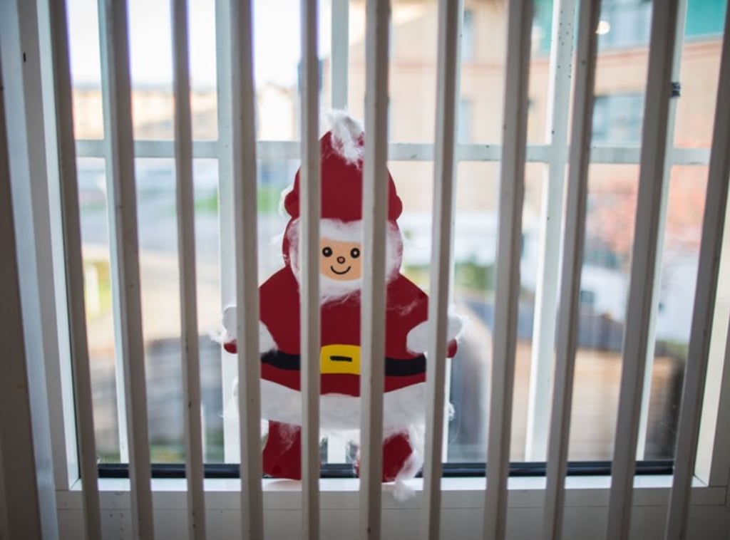 Ein gebastelter Weihnachtsmann klebt hinter einem Gitter in der Justizvollzugsanstalt an einer Fensterscheibe.