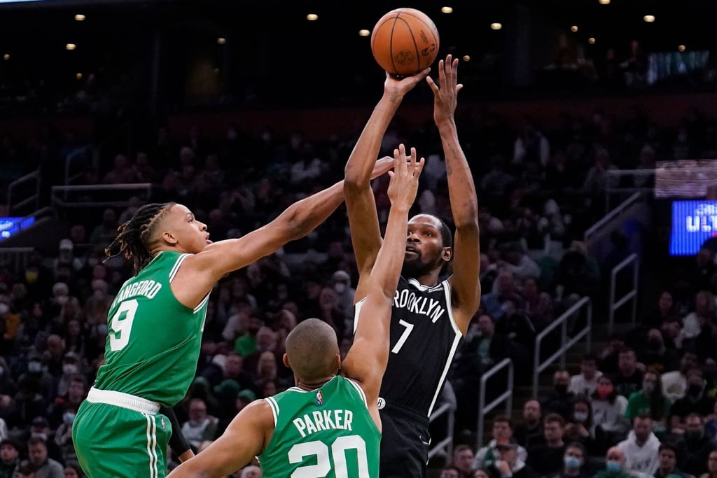 Brooklyn Nets-Forward Kevin Durant (r) wirft, während er von Boston Celtics-Guard Romeo Langford (l) und Forward Jabari Parker verteidigt wird.