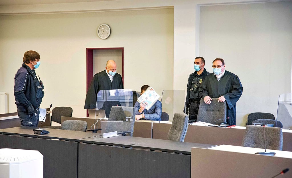 Der Angeklagte schützt sein Gesicht zum Prozessauftakt in Dessau mit einer Zeitung.