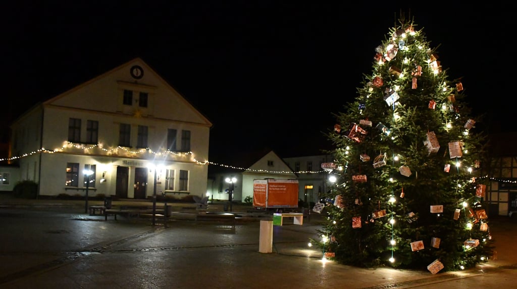 Der Arendseer Marktplatz ist vorweihnachtlich beleuchtet. In der Mitte steht nun eine Bank (grüne Füße), an der Handys aufgeladen werden können.