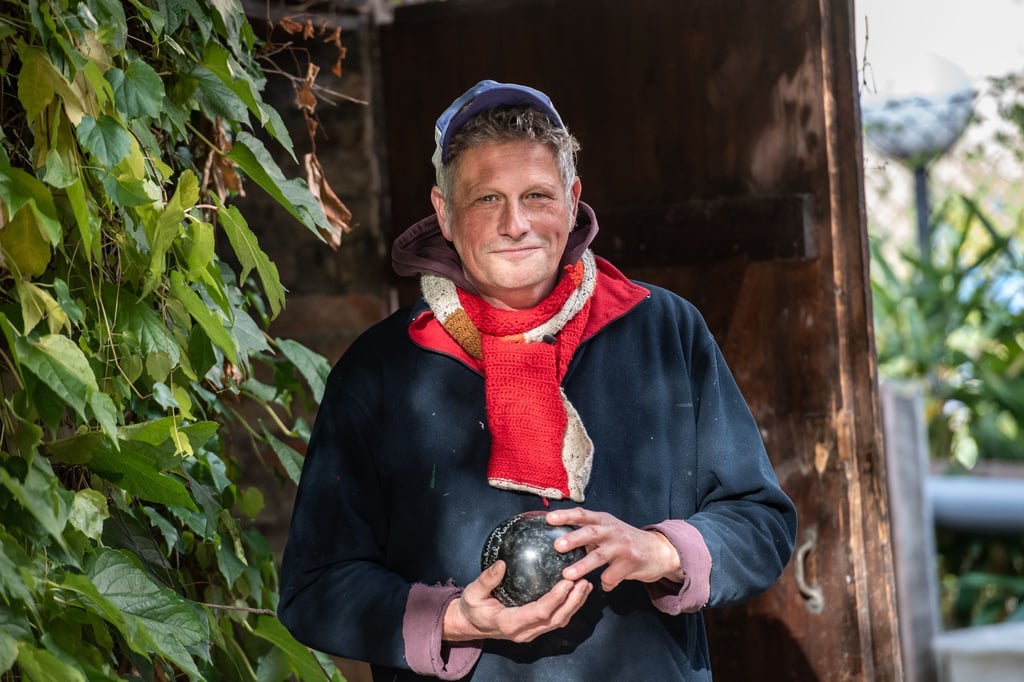 Bildhauer Todosch Schlopsnies (55) steht auf dem St. Jacobi Friedhof in Neukölln und hält eine steinerne Kugel in den Händen, die aus einem ehemaligen Grabstein entstanden ist.