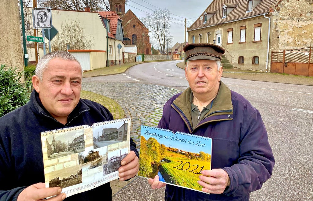 Heiko Scharf (links) und Eckhardt Scholz mit dem neuen und dem aktuellen Kalender vor einem der abgebildeten Häuser.