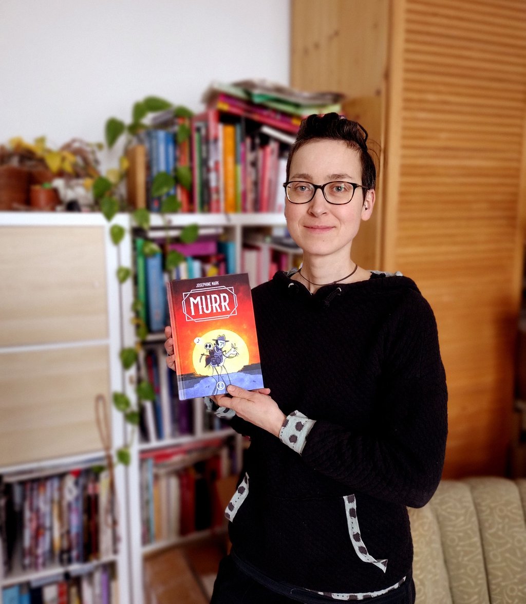 Die Comicautorin hält ihr aktuelles Buch in den Händen.