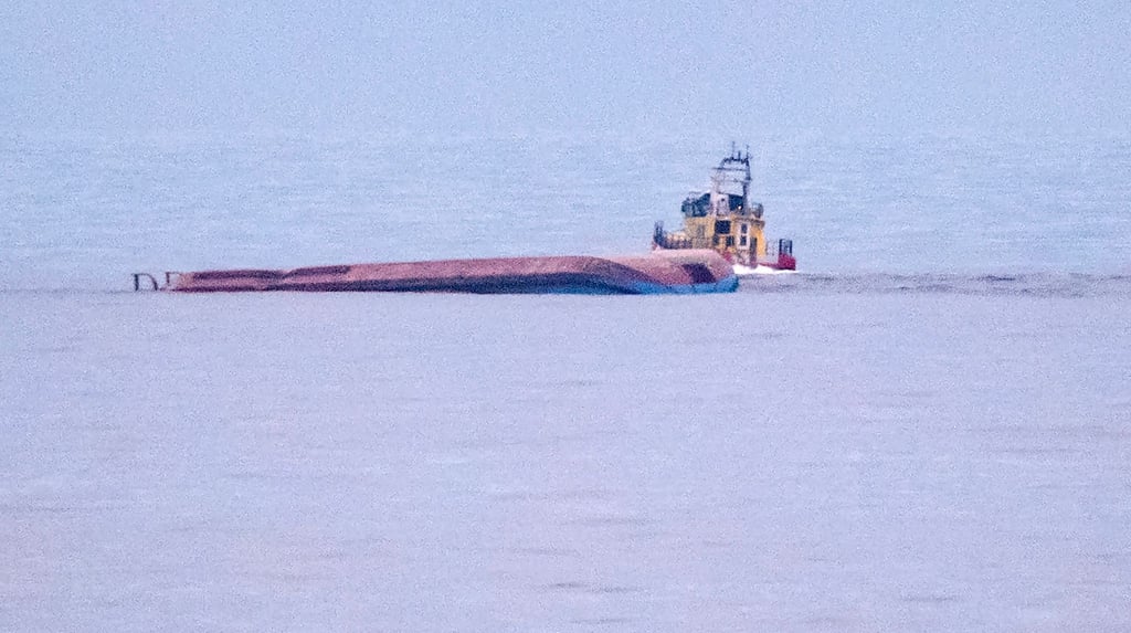 Ein Rettungsboot fährt an dem mit Kiel nach oben liegenden dänischen Frachtschiff Karin Hoej vorbei.