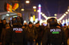 Polizisten vor einer Menschenansamlung die durch die Innenstadt von Magdeburg in Sachsen-Anhalt zieht.