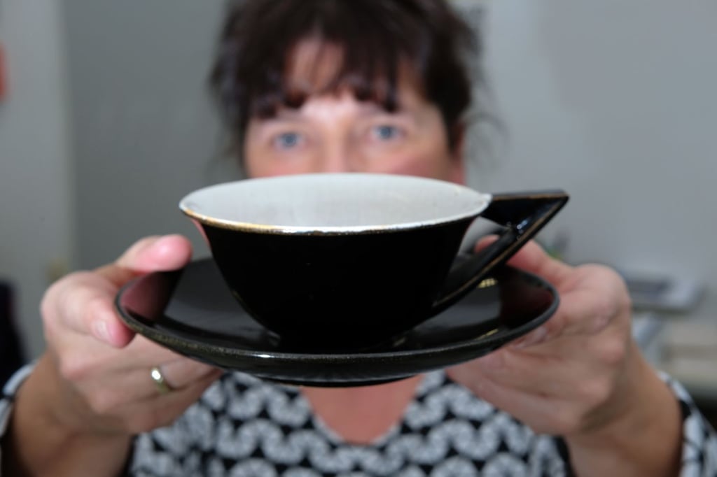 Eine Mitarbeiterin der Burg Giebichenstein Kunsthochschule Halle hält eine Tasse aus einem Teeservice aus Bürgel-Keramik.