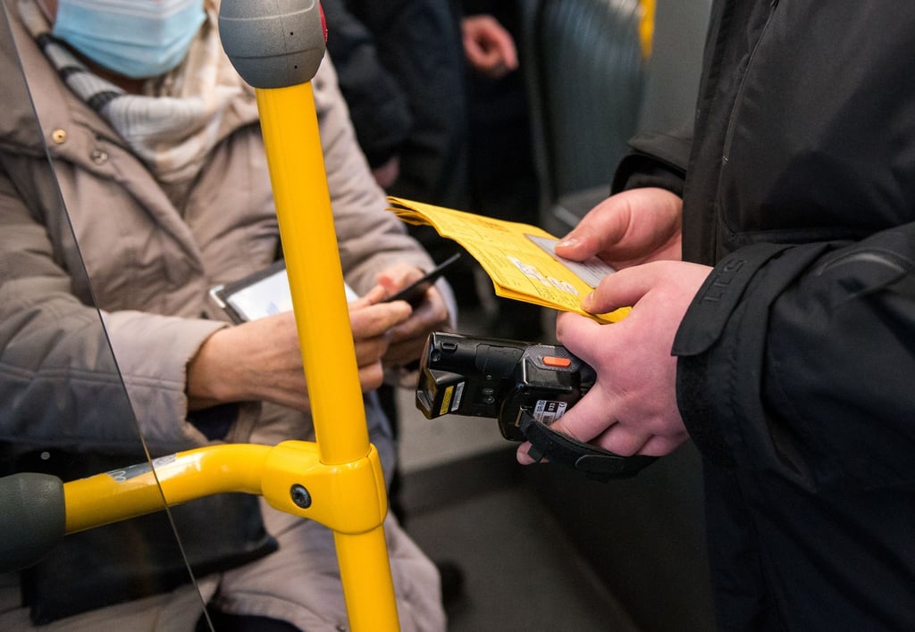 Ein Prüfdienst-Mitarbeiter der Verkehrsbetriebe Hamburg-Holstein (VHH) kontrolliert in einem Bus den 3-G-Nachweis einer Passagierin.